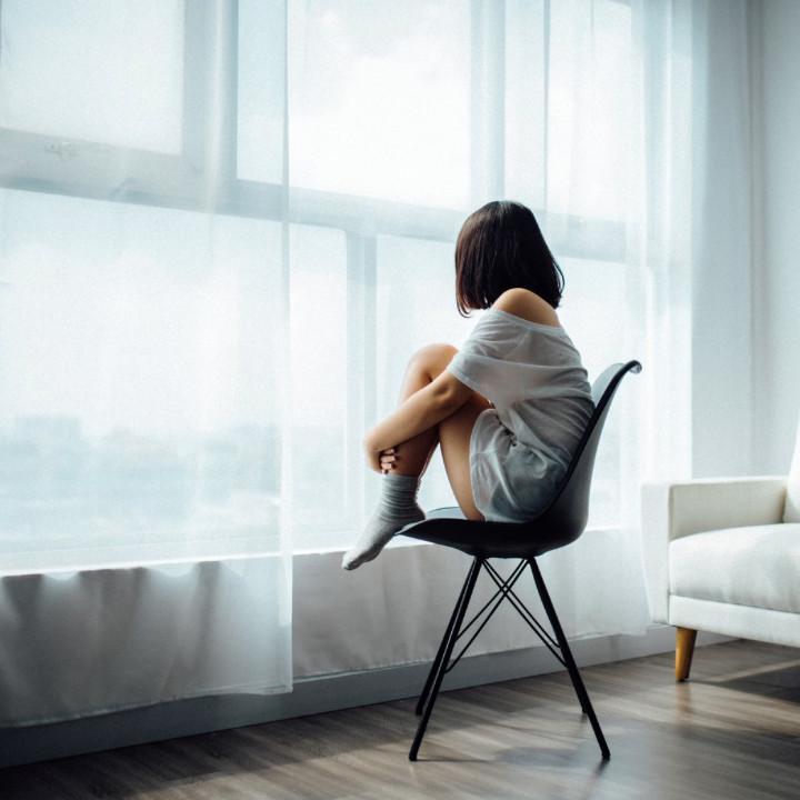 Woman reflecting while looking out of the window. Contemplative about moving out